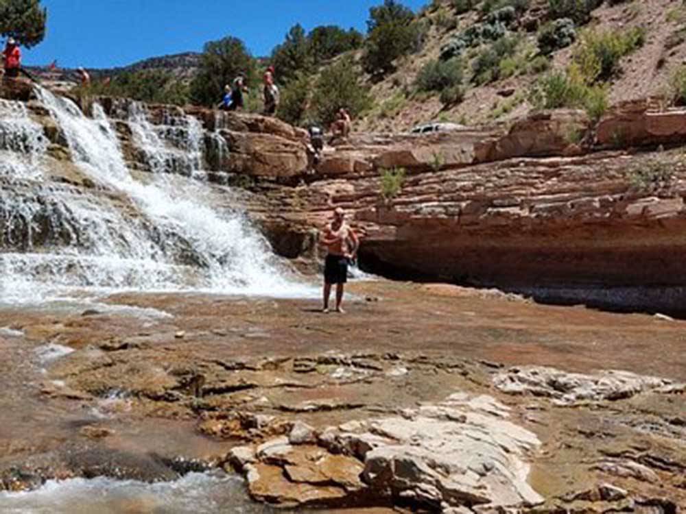 A man standing in the Toquerville Falls nearby at SETTLERS JUNCTION RV PARK