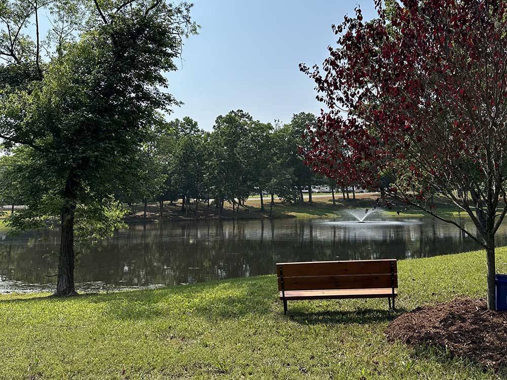 A bench next to the water with a fountain at BLAKE FARMS FAMILY RV RESORT