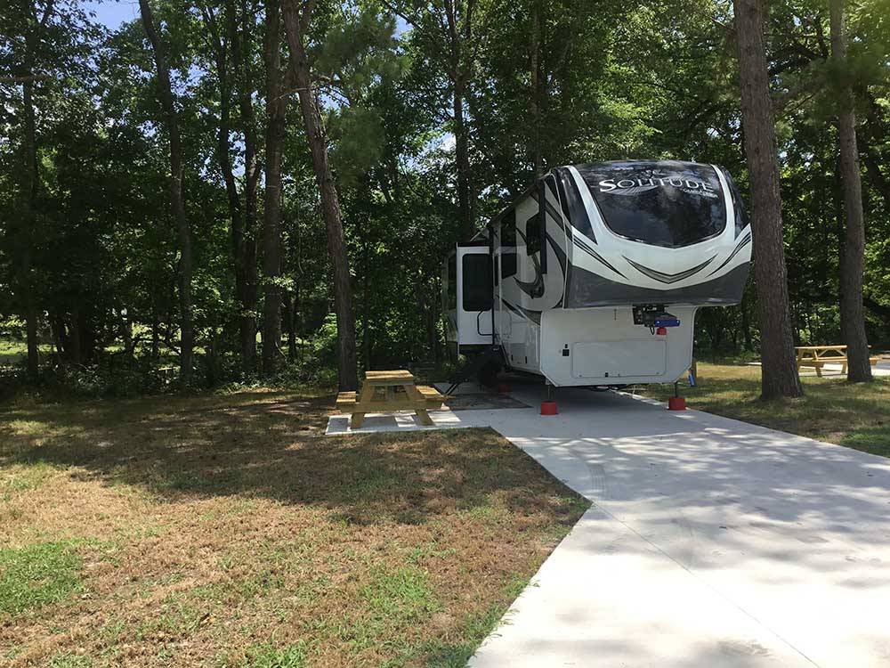 A fifth wheel trailer parked in a concrete site at TWO CREEKS CROSSING RV RESORT