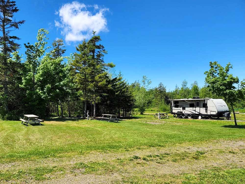 Large open campsites near a parked RV at THE RIDGE CAMPGROUND