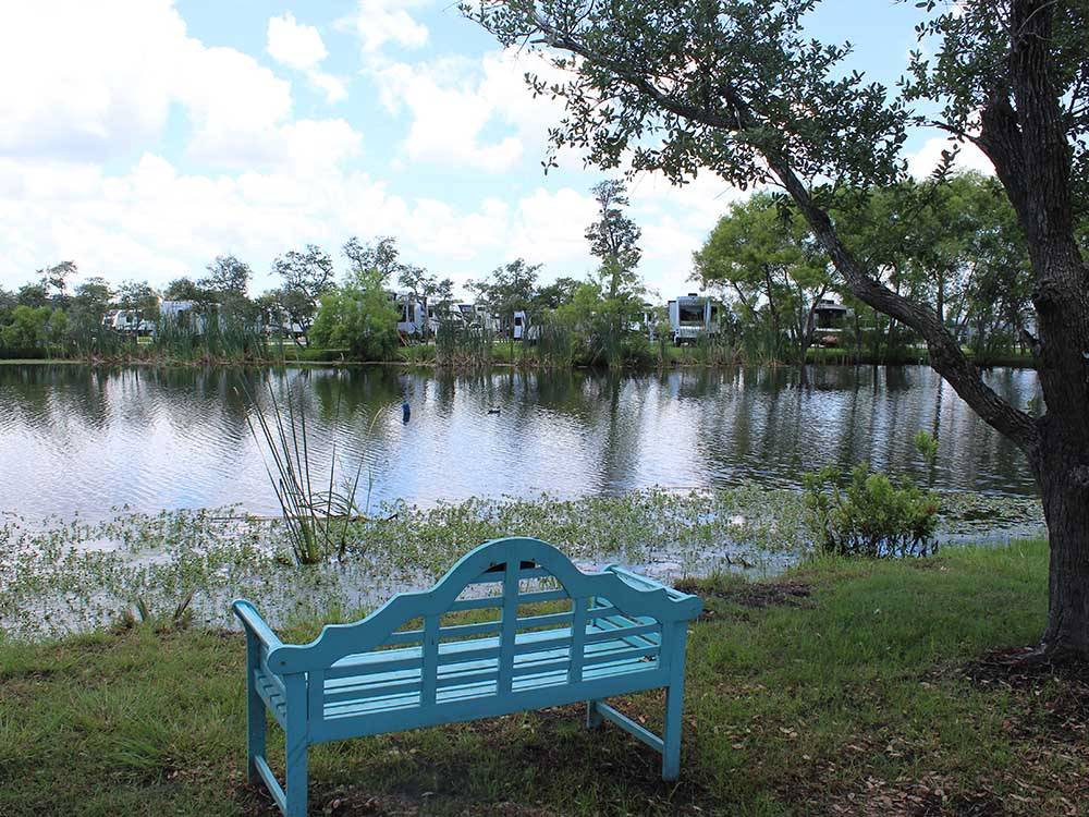 A blue bench next to the lake at SEA GRASS RV RESORT
