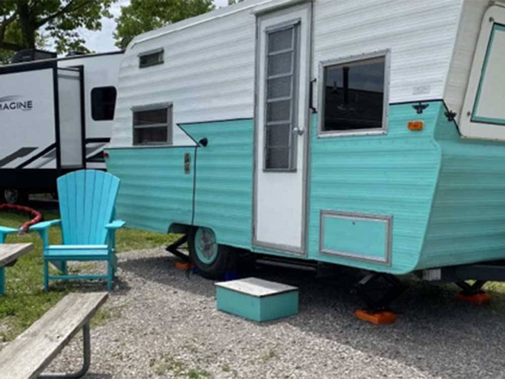 A vintage trailer next to two chairs at DANCING FIRE GLAMPING AND RV RESORT
