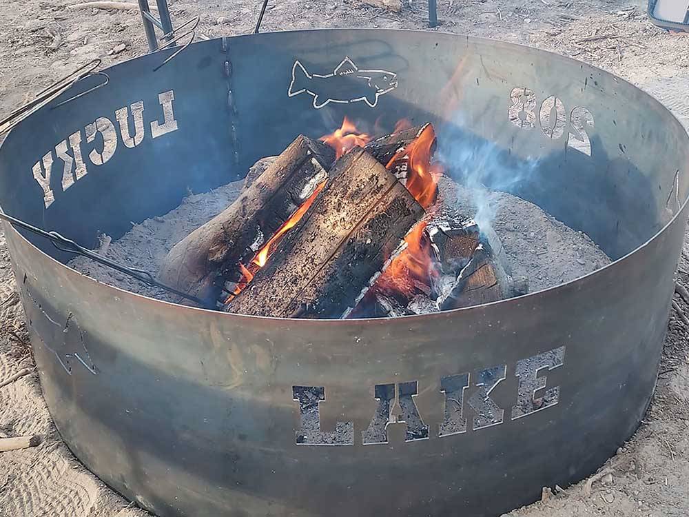 Logs burning in a pit with the park name on it at LUCKY LAKE 208