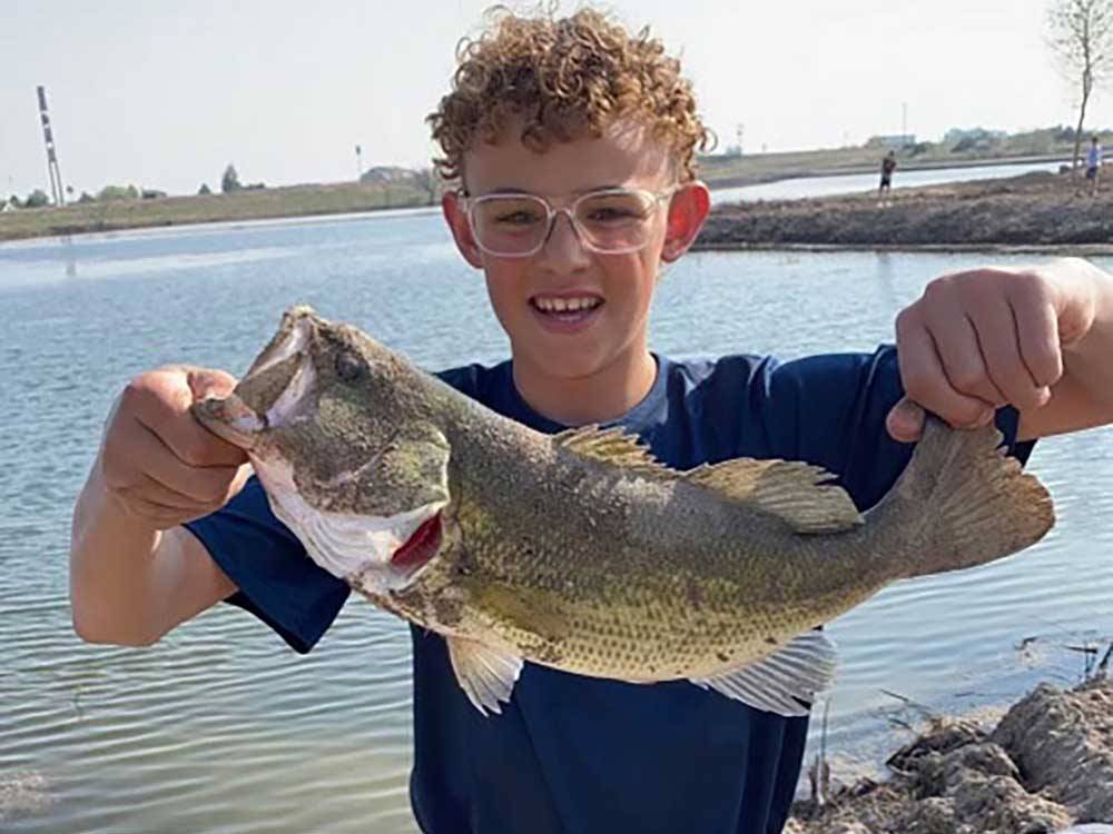 A boy holding up a fish he caught at LUCKY LAKE 208