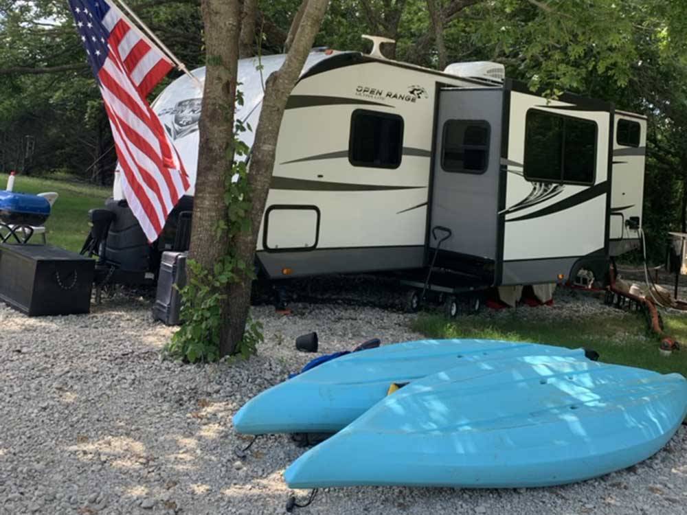 A travel trailer with blue kayaks next to it at SUNDOWNER RV PARK