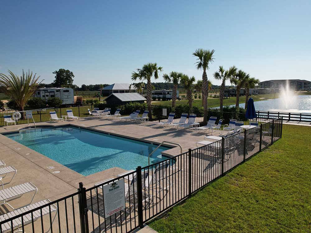 Fenced in swimming pool next to the lake at GRAND RIVIERA RV RESORT