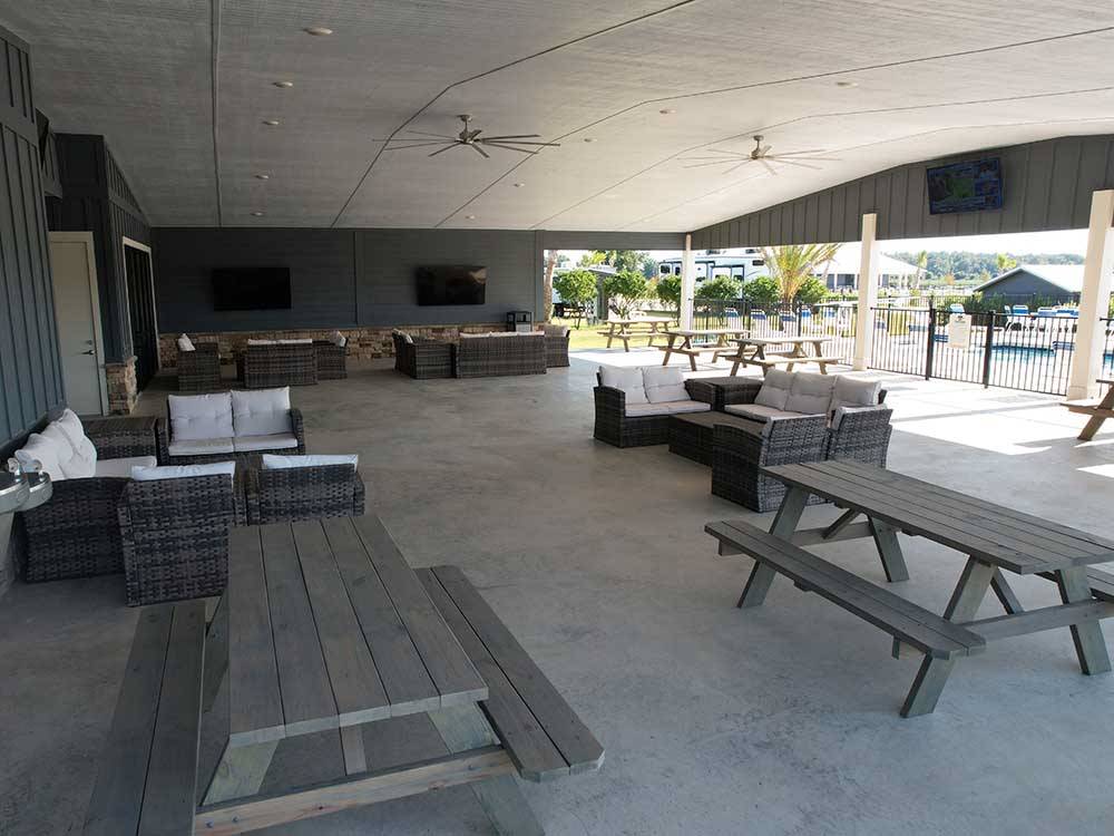 Couches and benches under a pavilion next to the swimming pool at GRAND RIVIERA RV RESORT