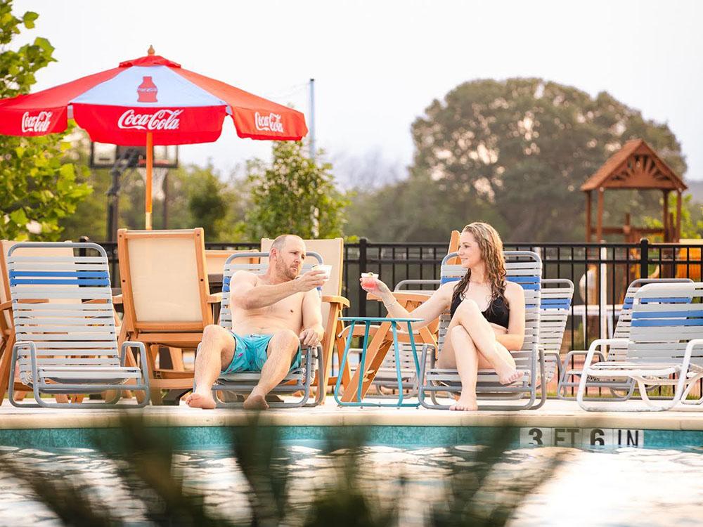 A couple sitting next to the pool at CAMP LANDA RV RESORT