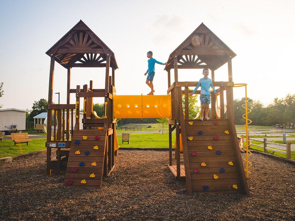 Kids playing on the wooden play structures at CAMP LANDA RV RESORT