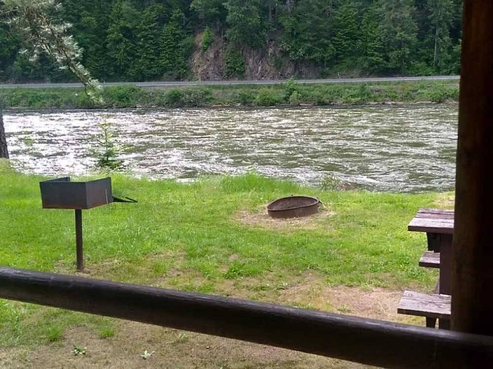 A bench and fire pit near the river at THREE RIVERS RESORT
