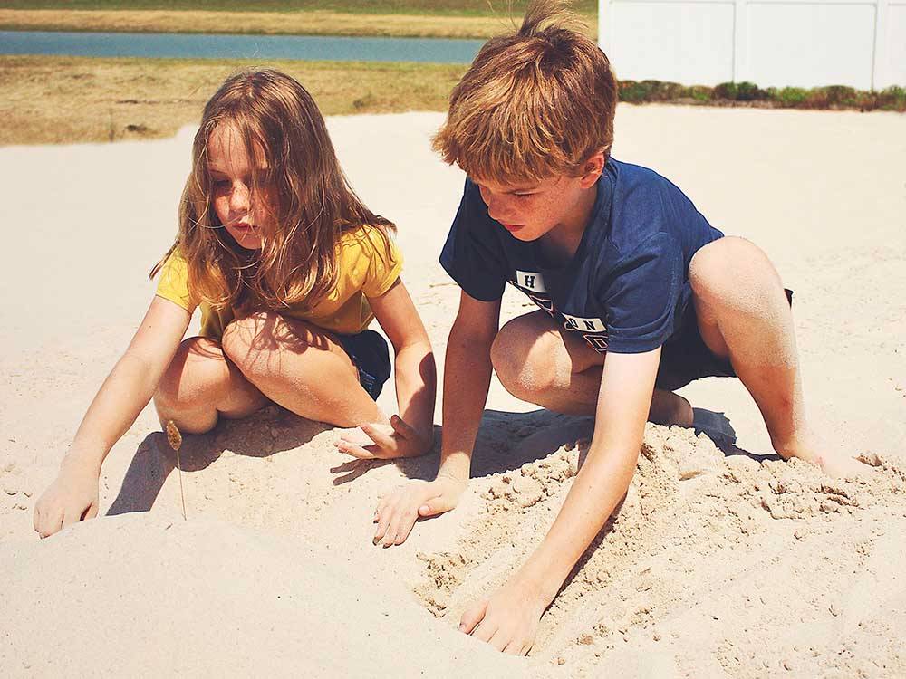 Two kids playing in the sand at LAKE DEWBERRY RV RESORT