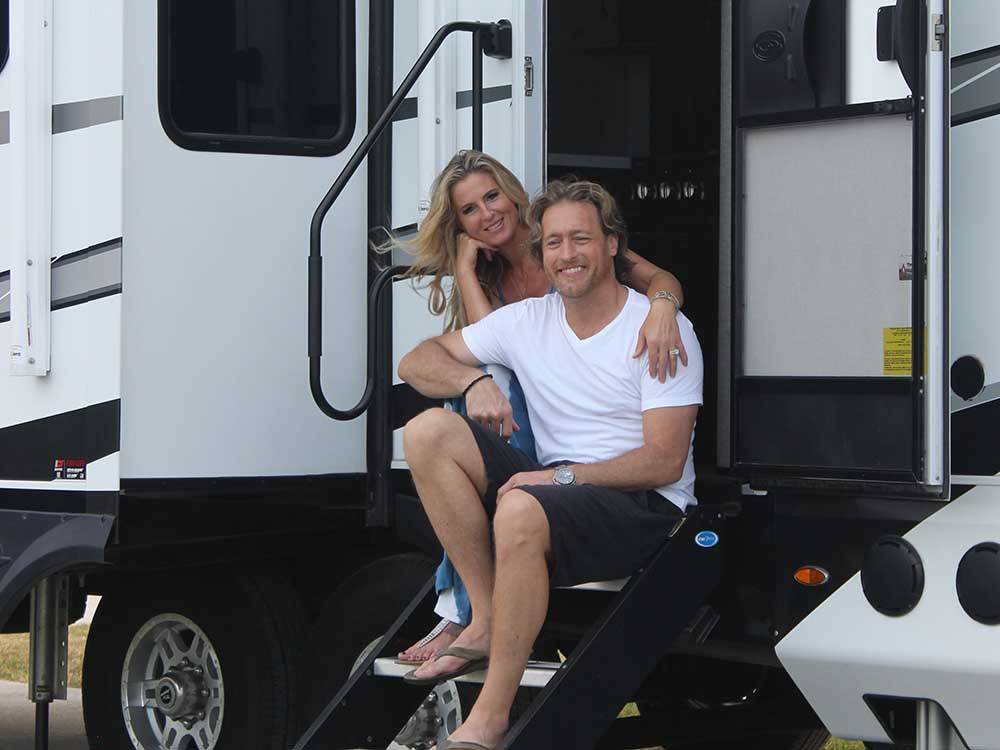 A couple sitting at the doorsteps of their RV at LAKE DEWBERRY RV RESORT