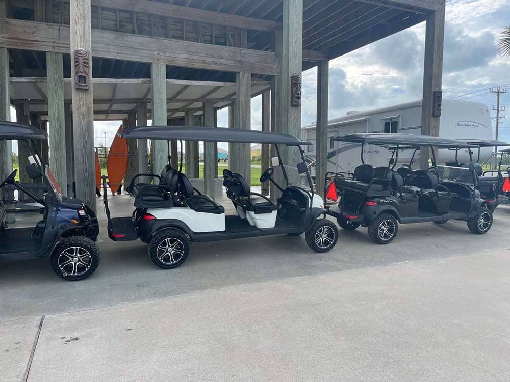 Golf carts parked under a wooden deck at THE PALAPA RV BEACH RESORT