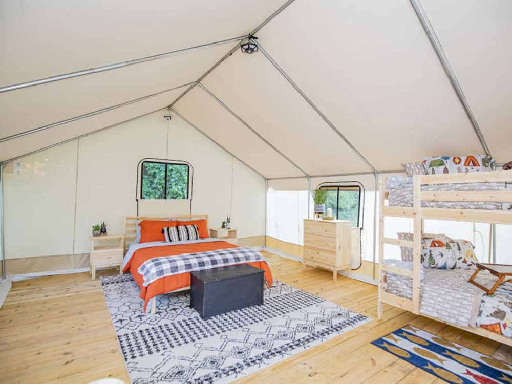 Bunk beds and a bed inside a glamping tent at ROARING RIVER HILLS CAMPGROUND AND CABINS