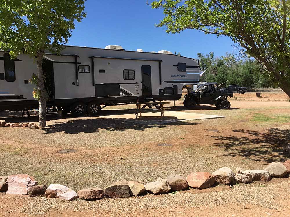 A fifth wheel trailer parked in a dirt site at SHEPHERD FAMILY CABINS & RV CAMPGROUND