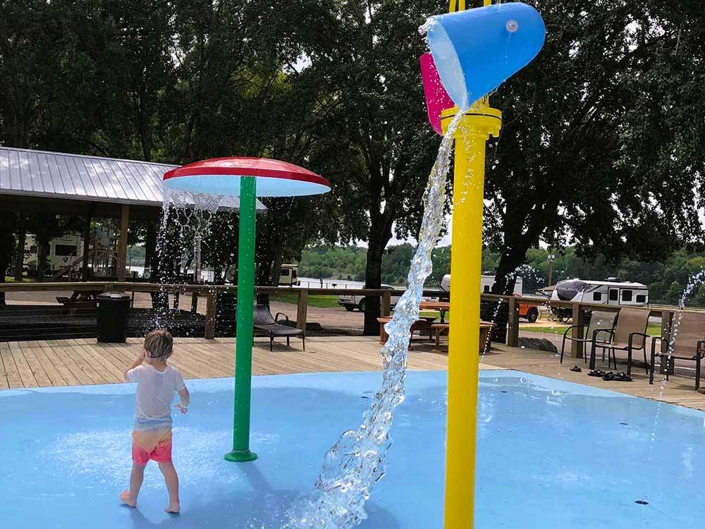 A boy playing in the splash pad at BOTEL CAMPGROUND