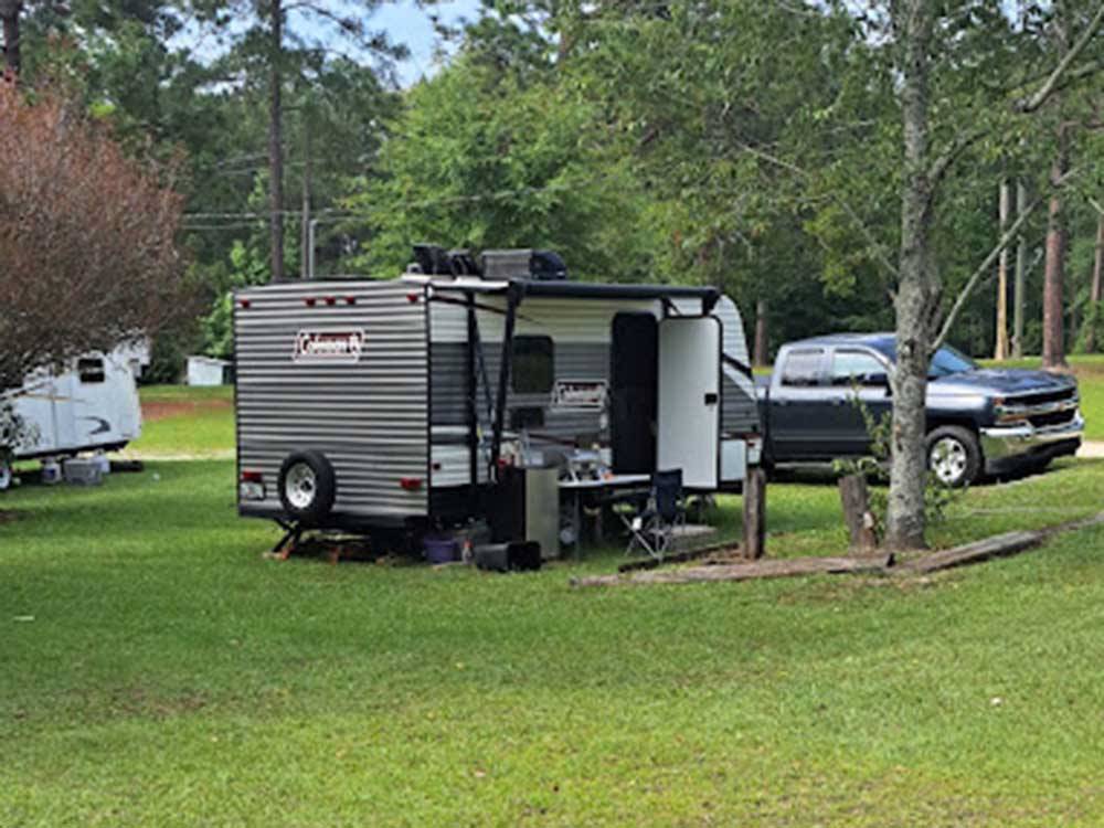 A travel trailer in a grassy site at HEAVENLY WATERS RV PARK