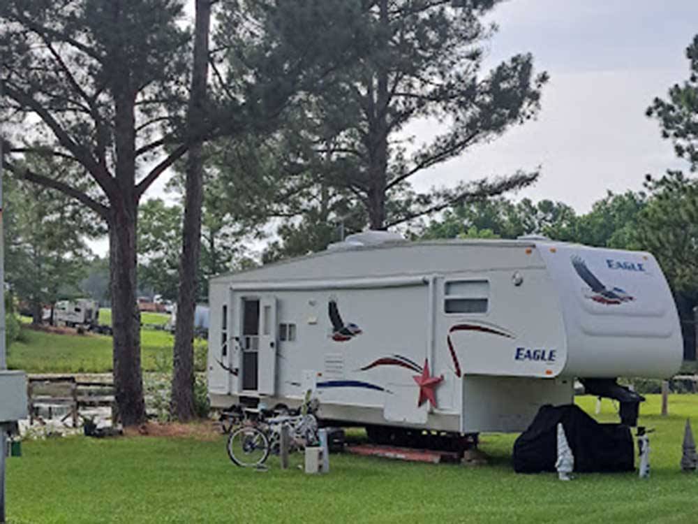 A fifth wheel trailer parked under a tree at HEAVENLY WATERS RV PARK