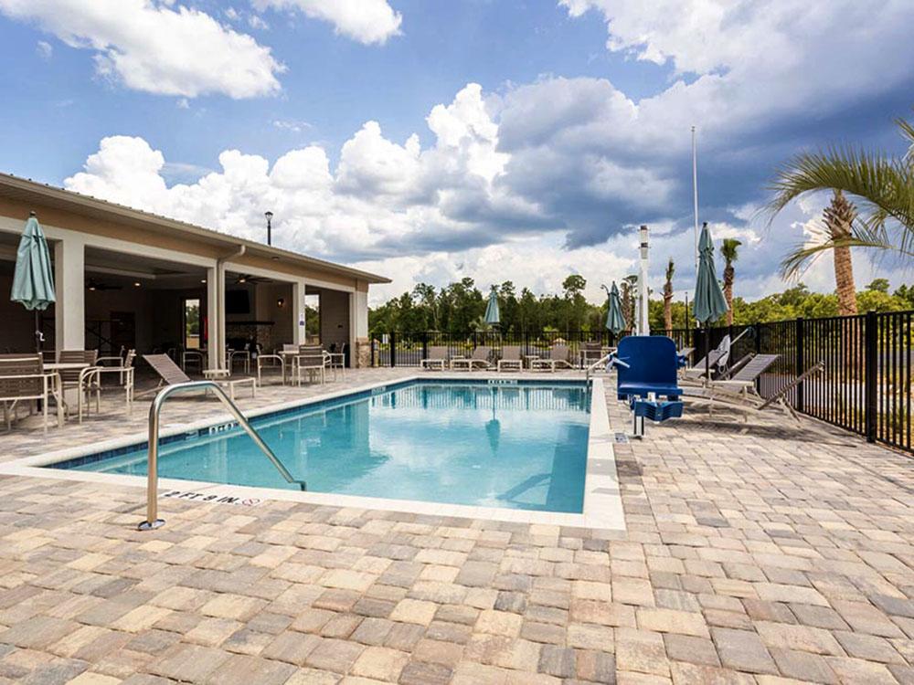 Lounge chairs in the swimming pool area at SANTA FE PALMS RV RESORT