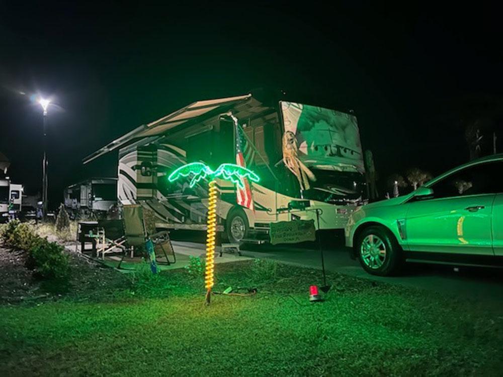 A Class A motorhome parked in a site with a palm tree light lit up at SANTA FE PALMS RV RESORT