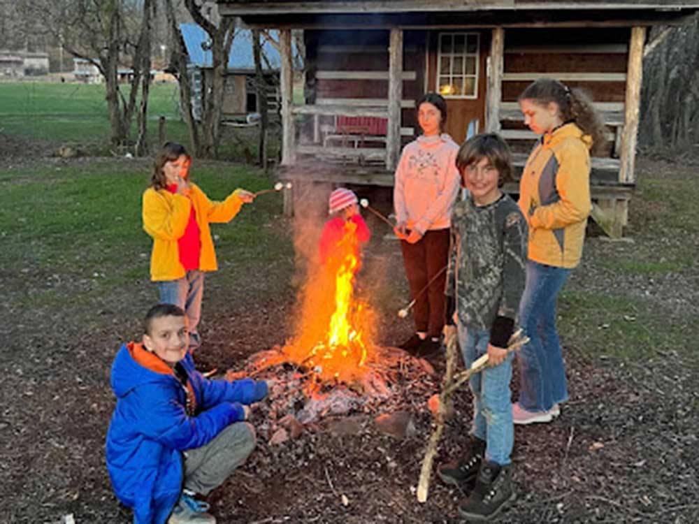 Kids roasting marshmallows at the fire pit at HEAVENLY HILLS NATURE RETREAT