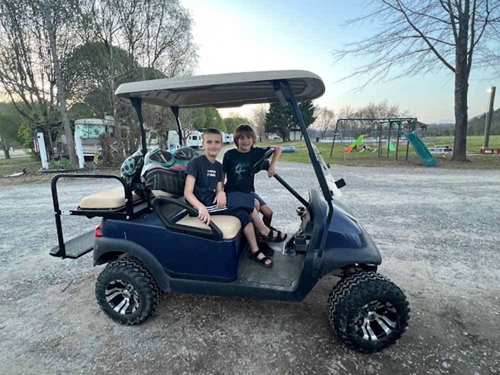 Two kids sitting in a golf cart at HEAVENLY HILLS NATURE RETREAT