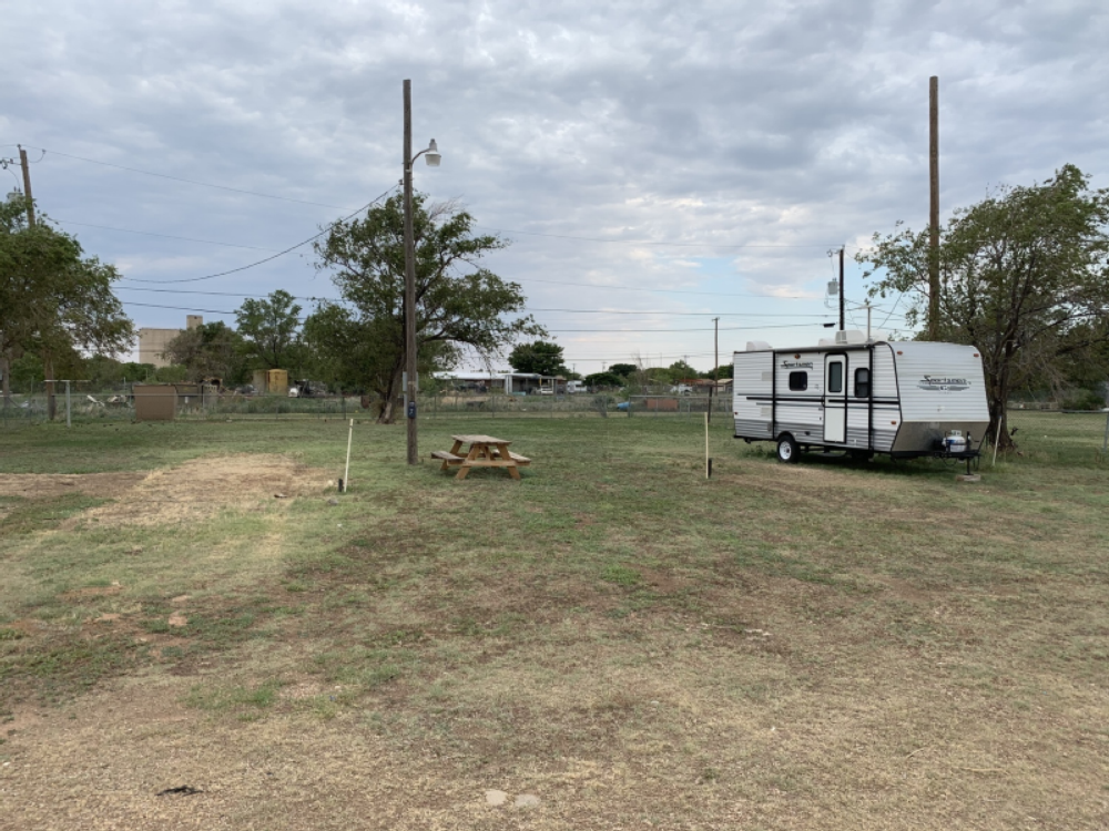 Trailer and table in grass site at Windmill Ranch RV Park & Cabins