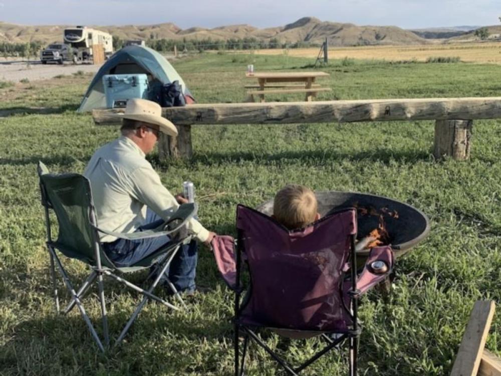 Man and son sitting by the fire pit at Crippled Spider RV Park & Campground