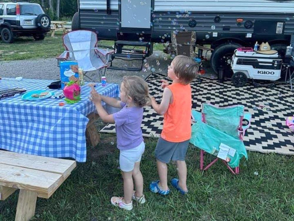 Kids blowing bubbles at their site at THE LANDING STRIP CAMPGROUND