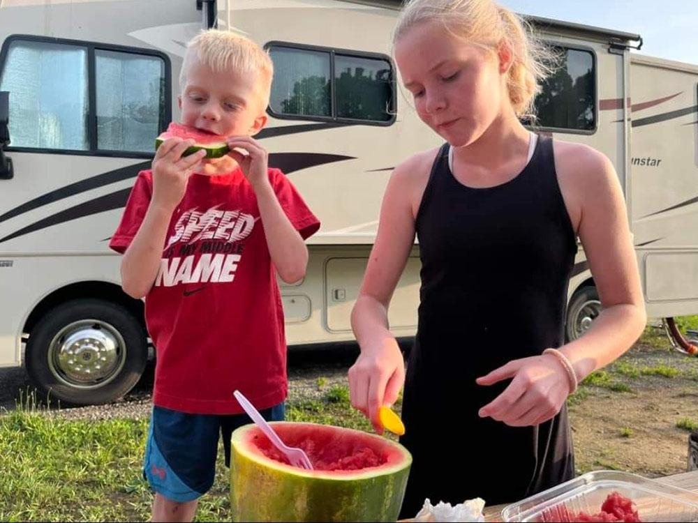 Two kids eating watermelon at THE LANDING STRIP CAMPGROUND