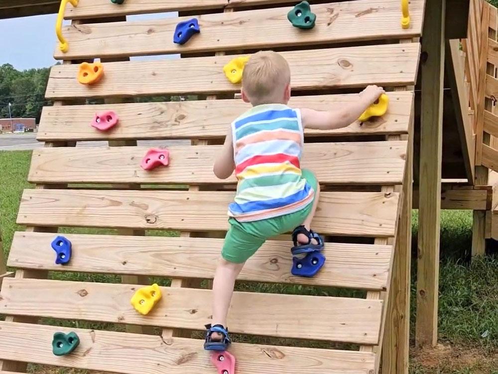 A boy climbing on the playground at THE LANDING STRIP CAMPGROUND