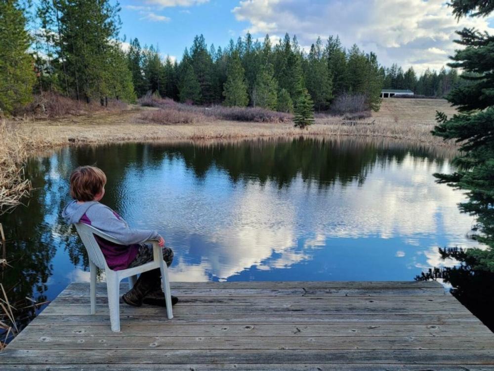 Kid sitting on a dock near the pond at Praeder Ranch Resort