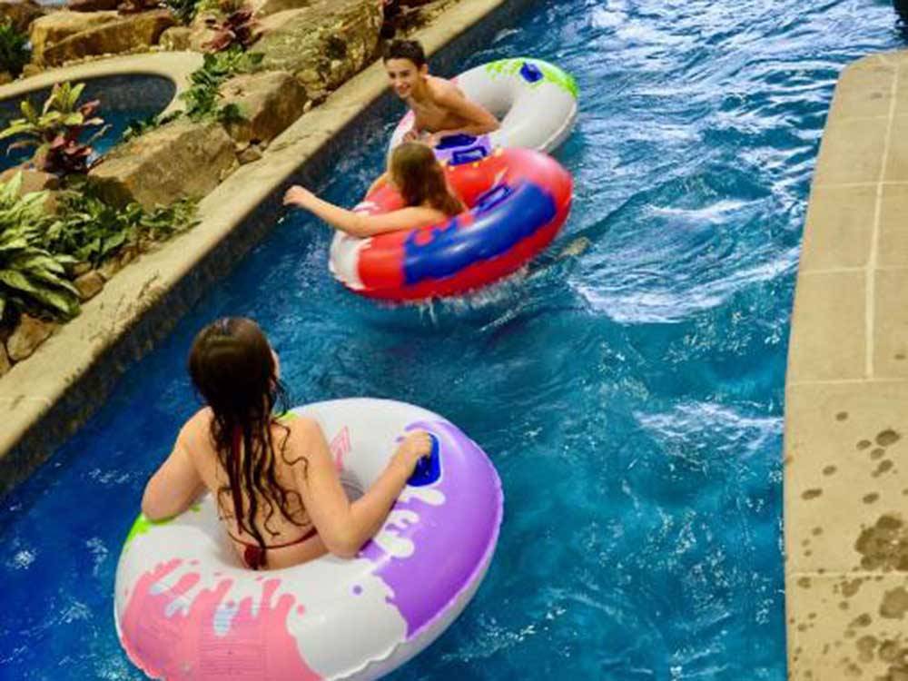Three kids in inner tubes in the lazy river at THE RV PARK 7 CLANS FIRST COUNCIL