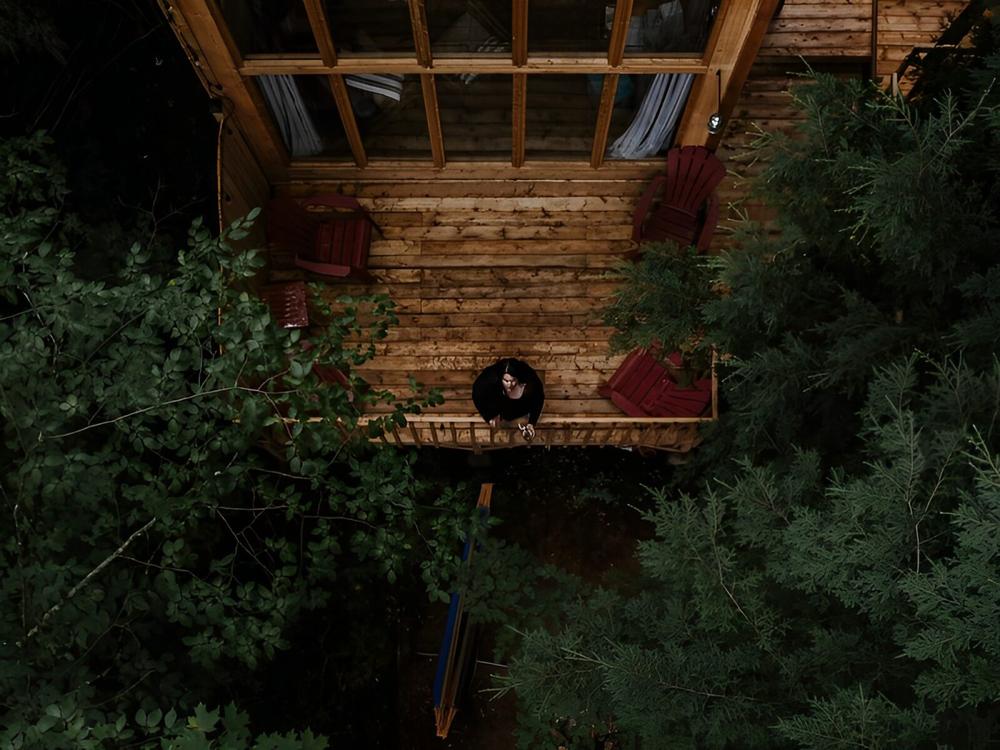 Woman on balcony looking up at trees