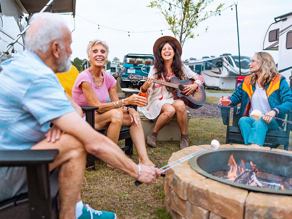 Group of people gathering around a fire pit at OCEANS RV RESORT