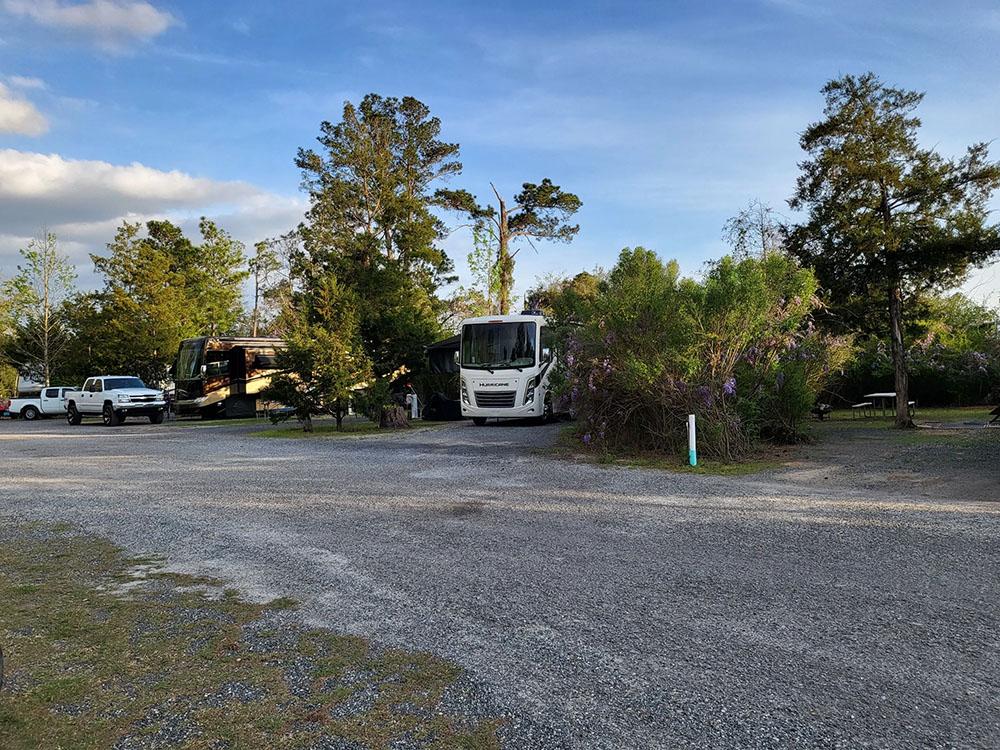 Gravel drive with view of several camp sites at HITCHINPOST RV PARK AND CAMPGROUND