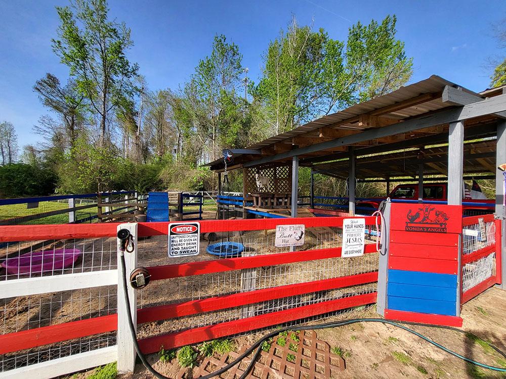 Outside view of petting farm with red fence at HITCHINPOST RV PARK AND CAMPGROUND