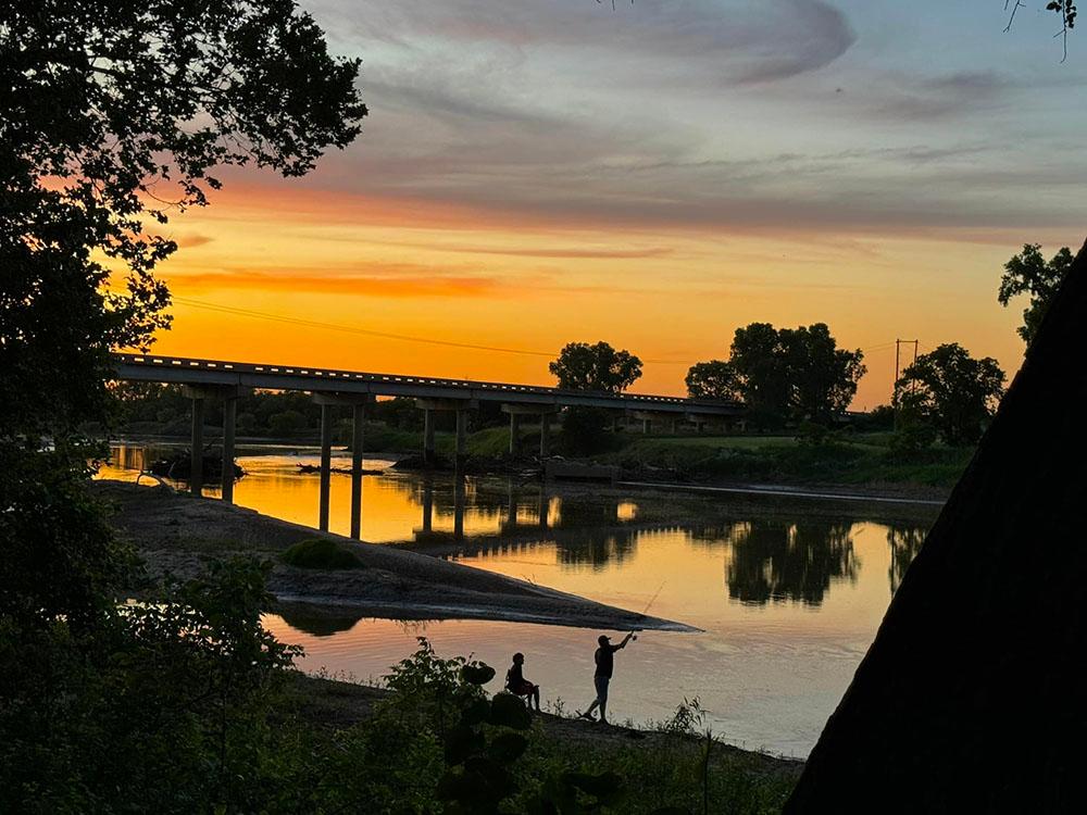 People fishing along river at sunset at RIVERSHIRE RV RESORT & CAMPING