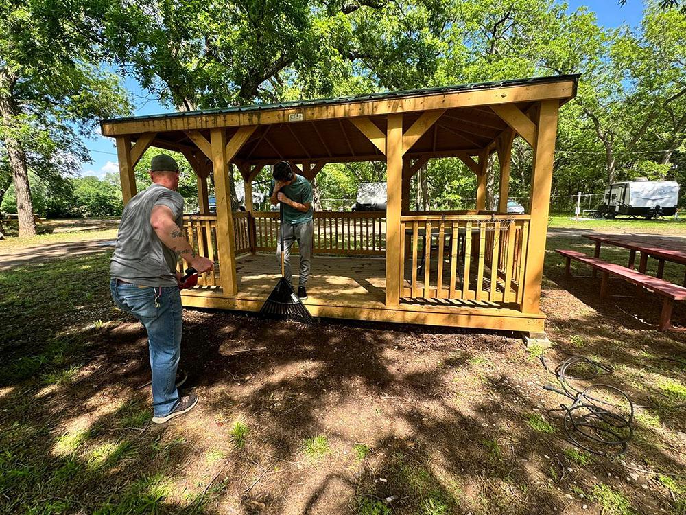 Two men working around the gazebo at RIVERSHIRE RV RESORT & CAMPING