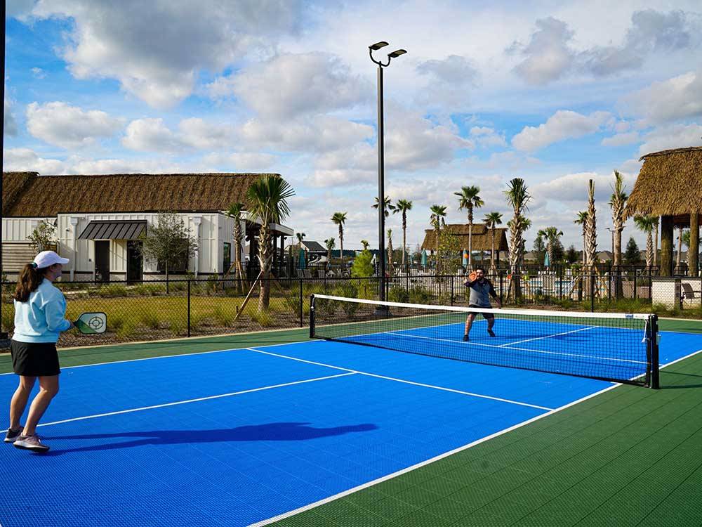 A couple playing pickleball at TROPIC HIDEAWAY RV RESORT