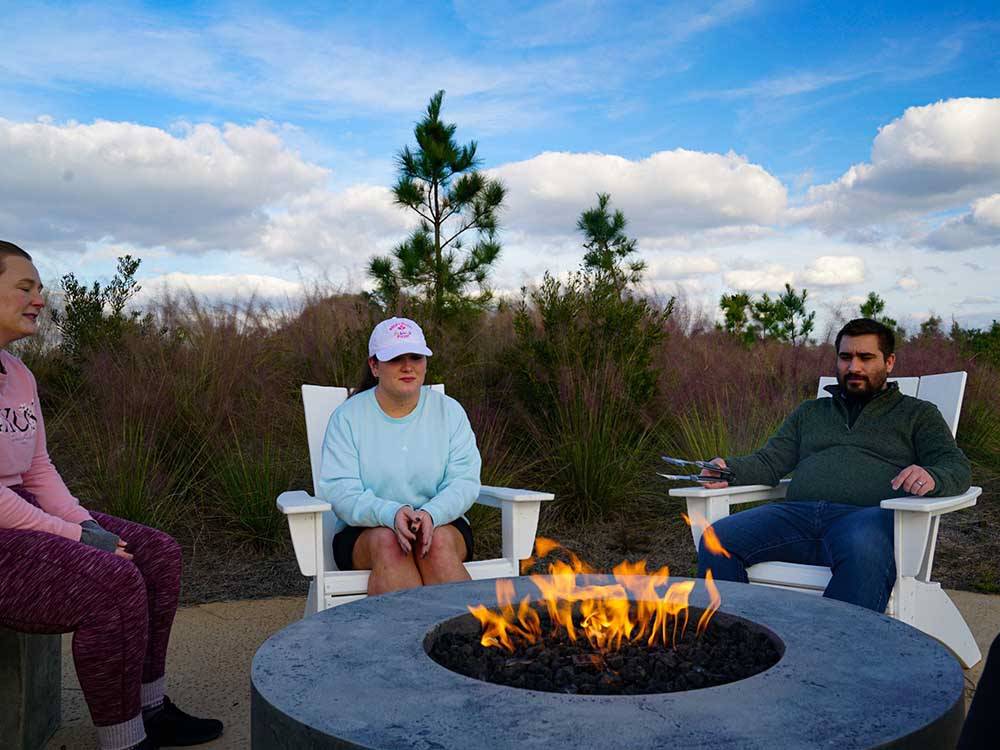 Couples sitting around a fire pit at TROPIC HIDEAWAY RV RESORT