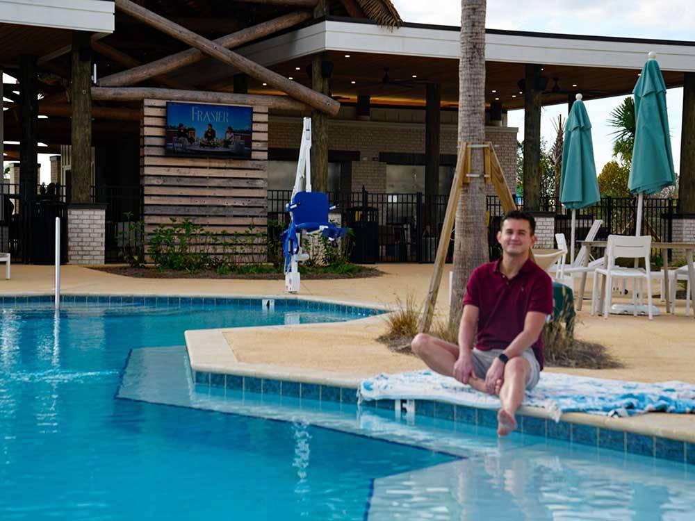 A man with his feet in the pool at TROPIC HIDEAWAY RV RESORT