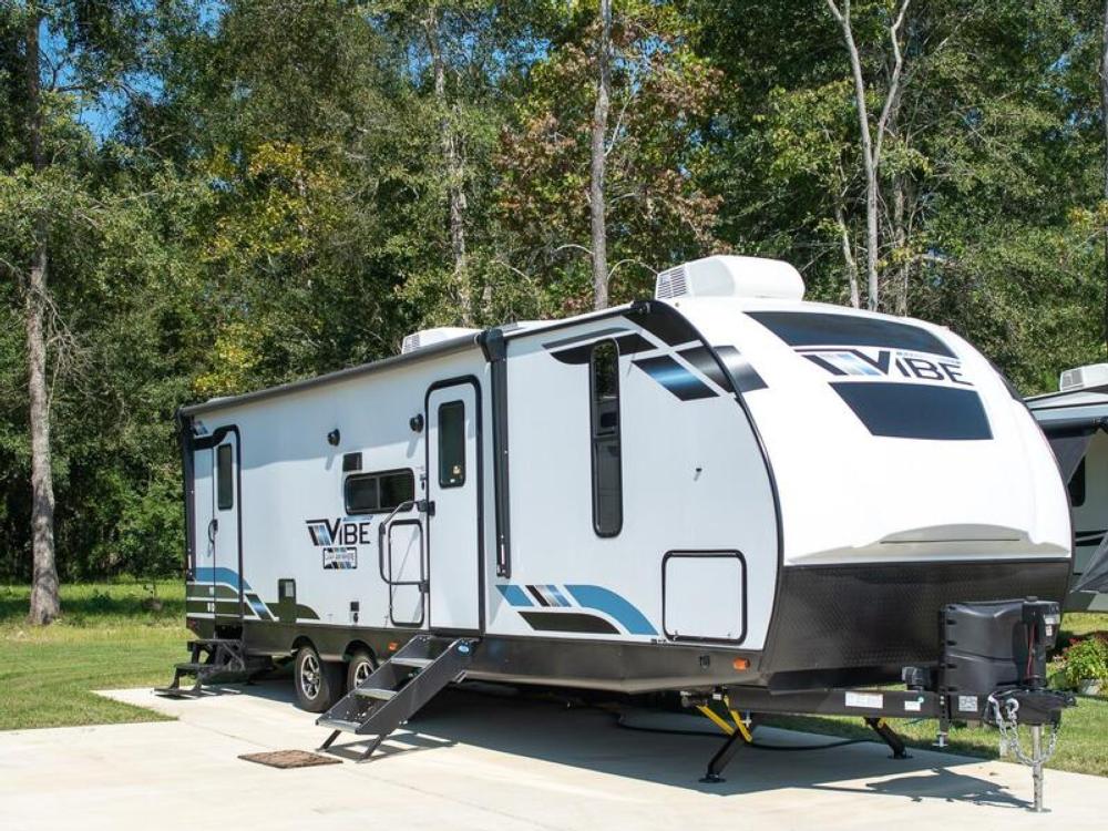 Travel trailer parked on paved site at The Retreat RV Resort & Camping