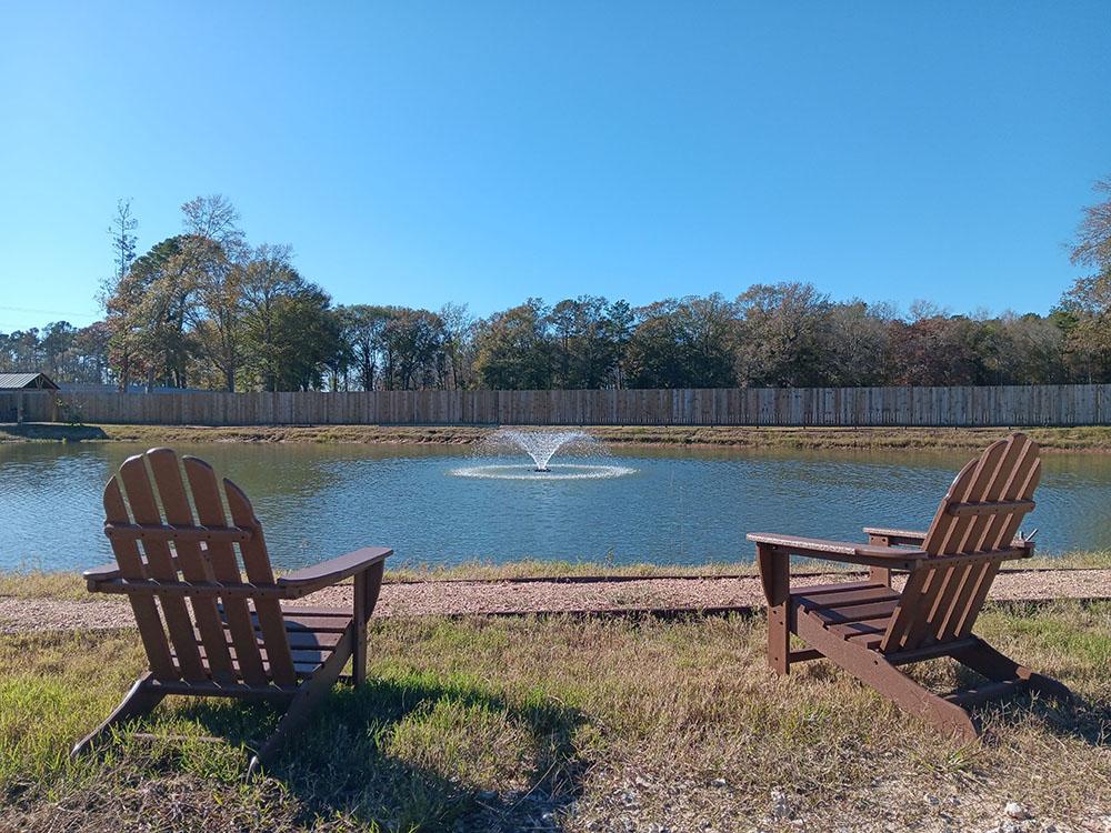 Two Adirondack chairs next to the lake at NEW CANEY RV PARK