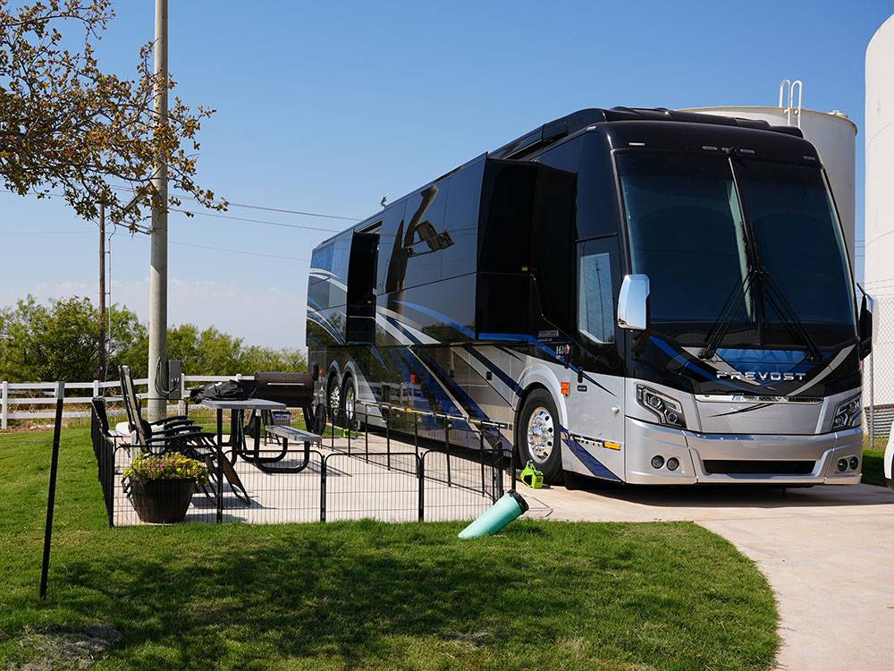 A Class A motorhome in a paved site with patio at Crossroads Luxury RV Park