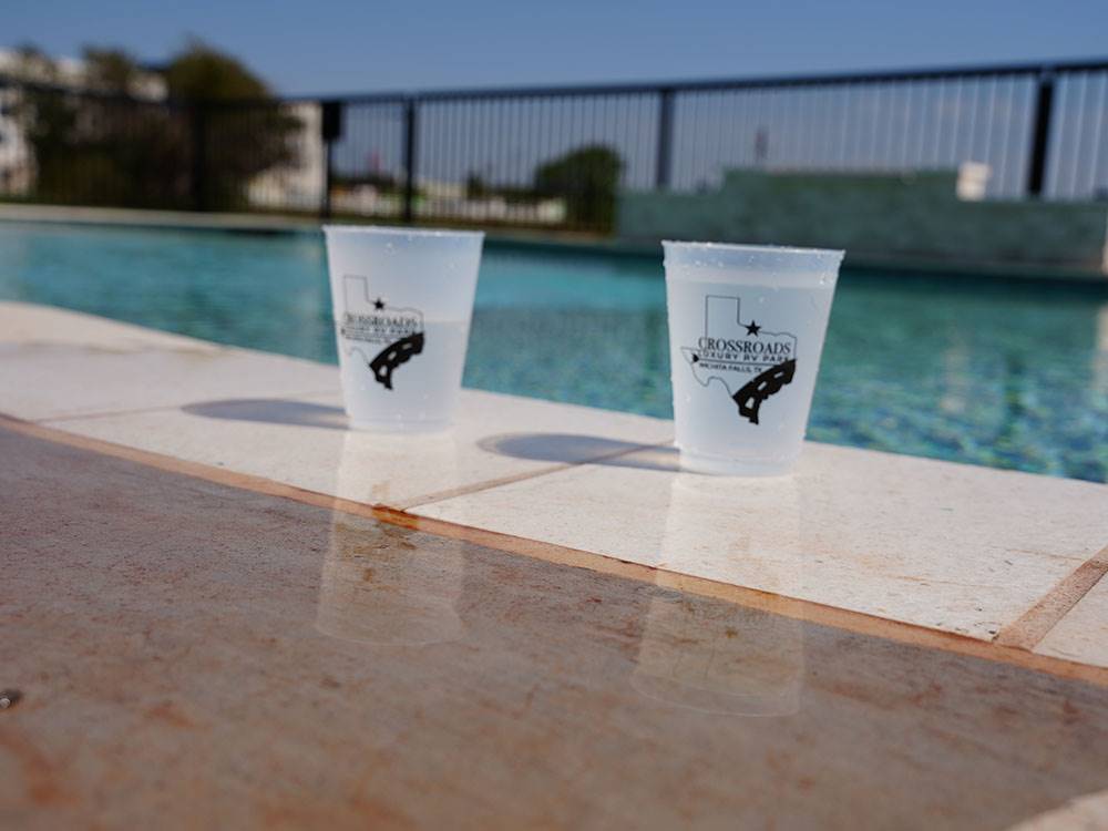 Two drinks on the edge of the pool at Crossroads Luxury RV Park