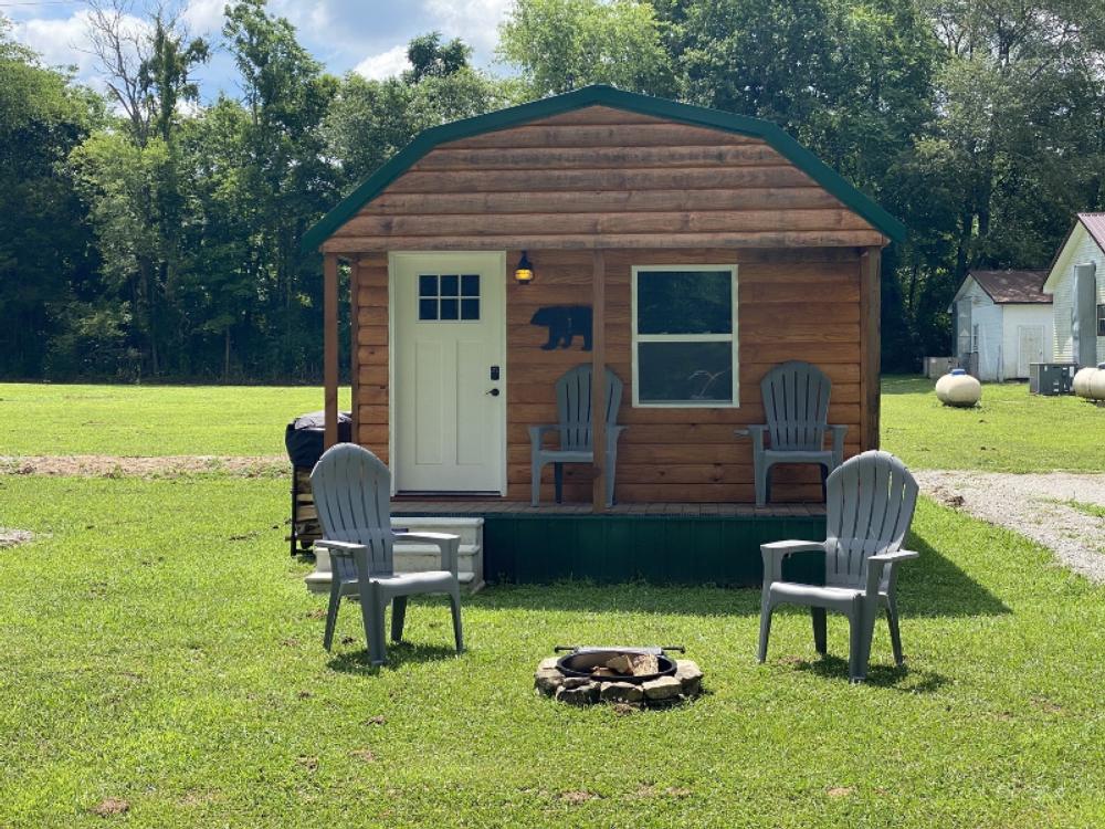 Little cabin with porch, fire ring and chairs at Big Mouth Cave Retreat