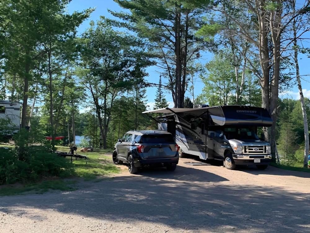 SUV and RV in gravel site at Wildwood Outdoor Adventures and Campground