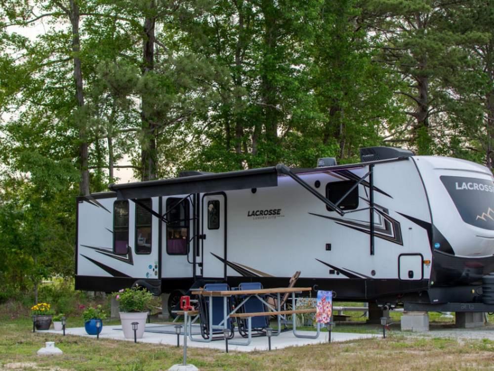 Paved pad by grassy site The Lakes RV & Cabin Resort