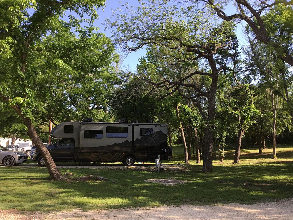 A trailer parked in a shady RV site at BRAZOS RIVER HIDEOUT